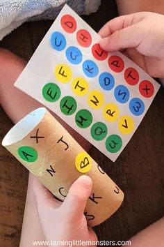 a child holding a paper roll with letters and numbers on it, while another child holds a cup in their hand