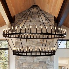 a large chandelier hanging from the ceiling in a living room with stone walls