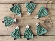 six crocheted christmas tree ornaments are arranged in a circle on a wooden surface