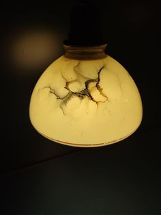 a light that is hanging from the ceiling with cracks in it's glass covering