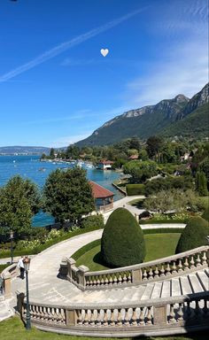 an aerial view of some steps and trees near the water with mountains in the background