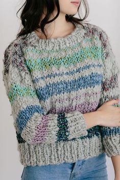 a woman wearing a gray sweater with multicolored stripes