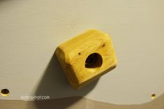 a wooden birdhouse hanging on the wall with holes in it's center hole