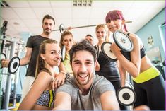 a group of people in a gym with dumbbells and weight plates on their shoulders