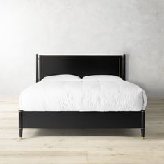 a bed with white sheets and black headboard against a gray wall in an empty room