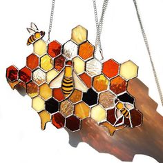 a stained glass bee and honeycomb suncath hanging from a chain on a white background