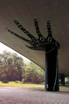 an artistically designed hand on the side of a building in front of some trees