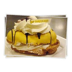 a banana split sandwich with whipped cream and bananas on top, sitting on a white plate