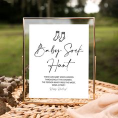 a baby soft heart sign sitting on top of a wicker basket next to rocks