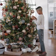 a young boy decorating a christmas tree with ornaments