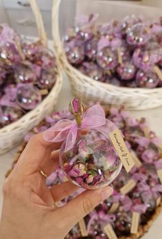 a hand holding a small glass ornament in front of some baskets filled with beads