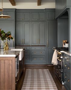 a large kitchen with gray cabinets and white counter tops, an area rug on the floor