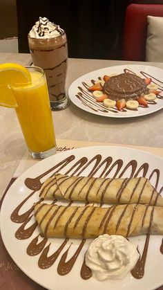 two desserts on plates with chocolate drizzle and orange juice