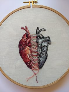 a cross stitched heart with two strings attached to it's sides, on a white background