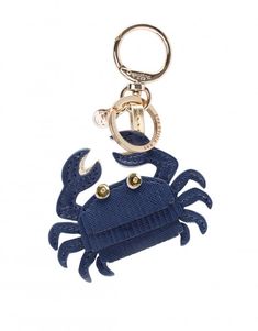 a blue crab keychain hanging from a metal hook on a white background,