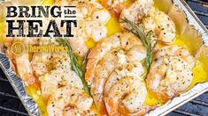 shrimp on the grill with lemon and rosemary garnish being cooked in foil container