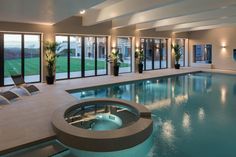 an indoor swimming pool surrounded by lounge chairs and large sliding glass doors leading to the outside