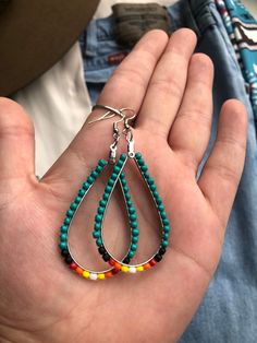 a person holding some kind of colorful beaded earring in their left hand,