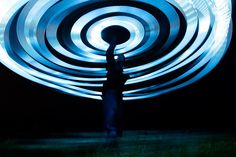 a person standing in front of a large circular object with blue lights on it's sides