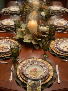 the table is set for thanksgiving dinner with plates, candles and napkins on it