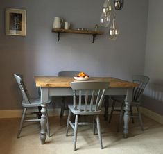 a dining room table with chairs and a bowl of oranges on top of it