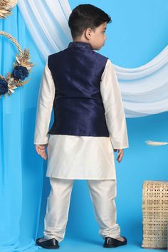 Navy blue embroidered nehru jacket in silk blend fabric, has mandarin collar, straight hemline, full front button placket with embroidered buttons. Cream color straight solid knee length kurta, has a mandarin collar, long sleeves, straight hem, button with button placket, side slits. Comes with cream solid pyjama, has elasticated waistband, slip-on closure.Vastramay present silk blend navy blue embroidered strappy square neck crop top with frill detailing. Comes with draped viscose skirt, has el Traditional Blue Sherwani For Spring, Blue Sherwani For Spring Festive Occasions, Blue Sherwani For Festive Spring Occasions, Blue Sherwani For Spring Festivities, Spring Blue Traditional Sherwani, Blue Traditional Sherwani For Spring, Blue Nehru Jacket With Resham Embroidery, Traditional Blue Bandhgala For Spring, Fitted Sets With Stand Collar For Eid