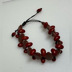 This Item Is A Handmade, Adjustable Bead Bracelet That Measures Approximately 8 Inches In Circumference. It Boasts A Combination Of Large Wooden Beads Paired With Striking Red, Oval-Shaped Beads, All Strung Together On A Durable Black Cord. The Adjustable Nature Of The Cord Ensures A Perfect Fit For Various Wrist Sizes, Providing Comfort And Ease To The Wearer. This Unique Accessory Is Ideal For Both Men And Women, Adding A Touch Of Rustic Charm And Natural Elegance To Any Outfit. The Bracelet's Adjustable Burgundy Bracelet, Adjustable Oval Bead Bracelets For Beach, Adjustable Large Beads Bracelet, Adjustable Beaded Bracelets With Oval Beads, Bohemian Red Beaded Bracelets With Heart Beads, Red Bohemian Beaded Bracelets With Heart Beads, Adjustable Red Beaded Bracelets With Wooden Beads, Handmade Adjustable Beaded Bracelets With Oval Beads, Adjustable Red Bracelet With Large Beads