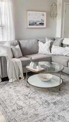 a living room with gray couches and white pillows on the rug, coffee table