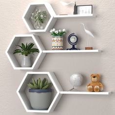 three hexagonal shelves with plants and stuffed animals on them, one is white