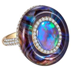 A 2.27 ct Solid Opal, Abalone Shell, Crystal and Diamond in 18k Yellow Gold. The solid opal is surrounded by a circle of diamond pave, on the outer circle is where the abalone shell is. The abalone shell is cover by thick crystal giving the ring a dome-like design. US Ring Size 8 Main opal weight is 2.27 ct Total diamond weight is 0.678 ct The diamonds are approximately E/F in colour with VS clarity