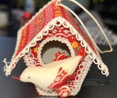 a red and white birdhouse ornament on a table