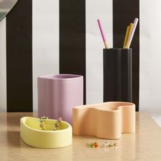 three different colored vases sitting on top of a wooden table next to each other