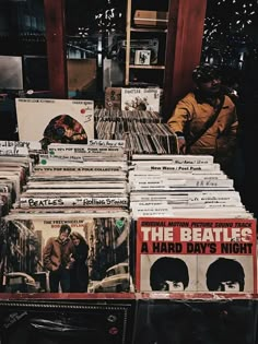 a man sitting in front of a table full of records and cds with the beatles logo on them