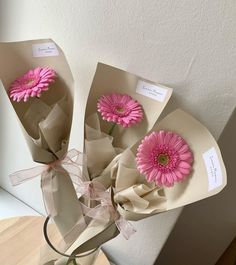 three pink flowers are in a vase on a table