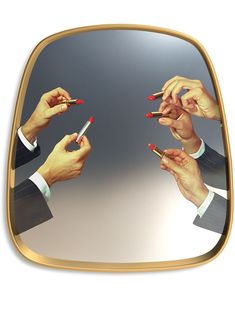 several hands holding pens and pointing at them in front of a mirror with the reflection of another person's hand