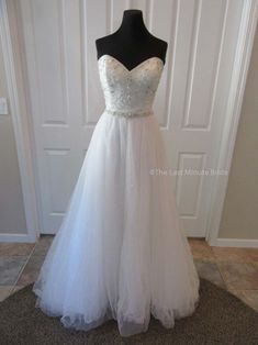 a white wedding dress on display in front of a door