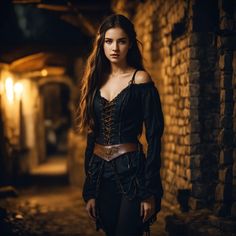 a woman wearing black clothing standing in an alley with brick walls and lights behind her