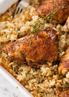 chicken and rice in a white casserole dish with a fork on the side