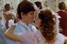 the young man and woman are kissing in front of other people at a dance party