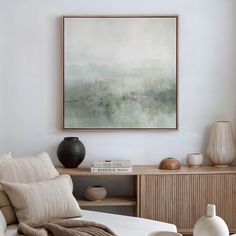 a living room filled with furniture and a painting hanging on the wall over a coffee table