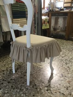 a white chair with a ruffled seat cover on top of it in a store