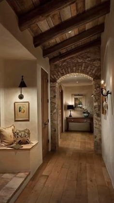 a long hallway with stone walls and wooden flooring is lit by two lights on either side of the room