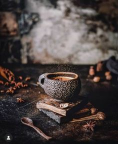 a bowl sitting on top of a wooden table next to some spices and cinnamons