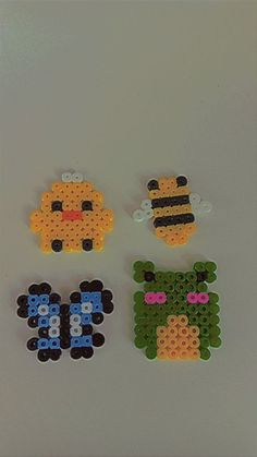 four pieces of bead art are arranged on a white surface, including one bee and the other two bees