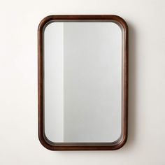 a mirror mounted to the side of a wall next to a wooden framed object on top of a white wall