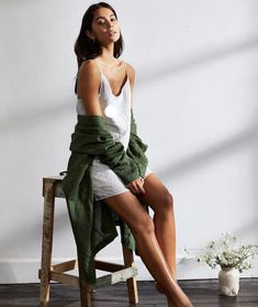 a woman is sitting on a chair with her legs crossed and looking off to the side