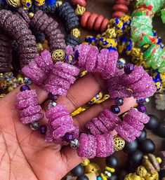 a hand holding a bunch of beads in it's palm next to bracelets