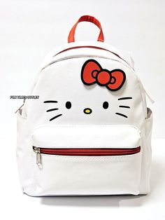 a white hello kitty backpack with an orange bow on the front and red zippers