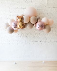 balloons are arranged in the shape of an owl and teddy bear on a white brick wall