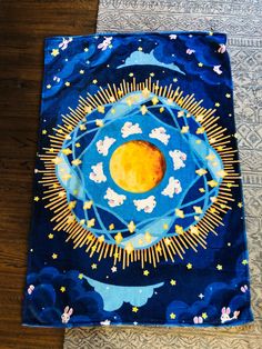 a blue and yellow cloth with an image of the moon in it on top of a wooden floor